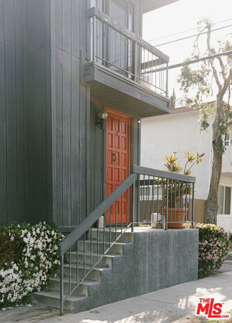 Front view of a two-story house with an orange door and a small balcony.