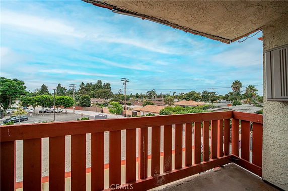 View from a balcony showing surrounding residential area and trees.