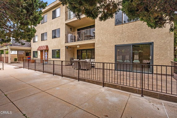 Front view of a multi-story building with balconies and a patio area.