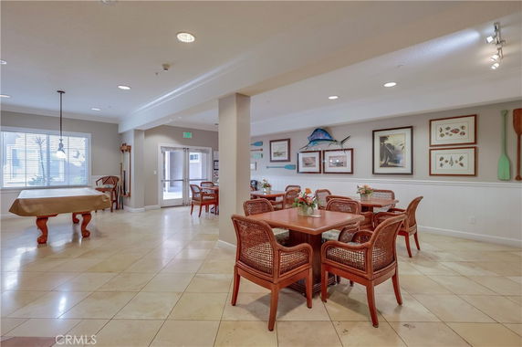 Interior view of a club house with tables and chairs, decorative wall art, and a pool table.