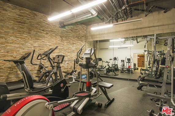Indoor gym area with exercise equipment and mirrored wall.