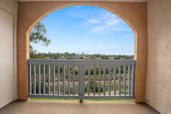View from a balcony showing surrounding landscape and distant trees.