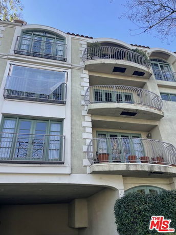 Front view of a multi-story building with balconies and green framed windows.