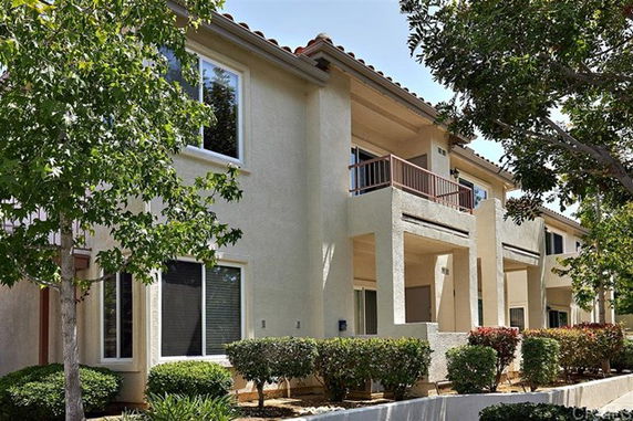 Front view of a two-story residential building with balconies and large windows.