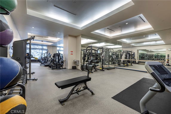 Indoor gym area with various exercise equipment and mirrors on the walls.