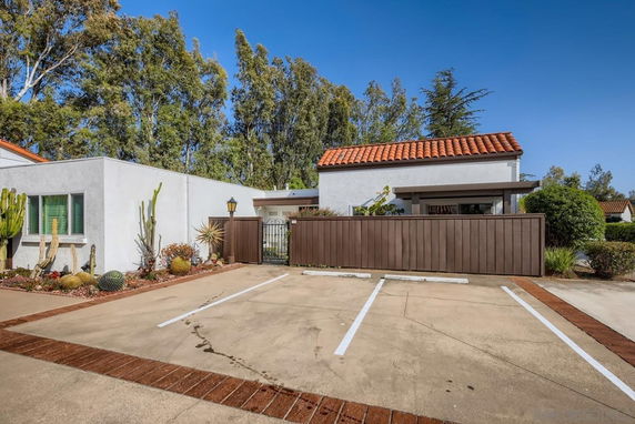Outdoor parking area in front of a house with a tiled roof.