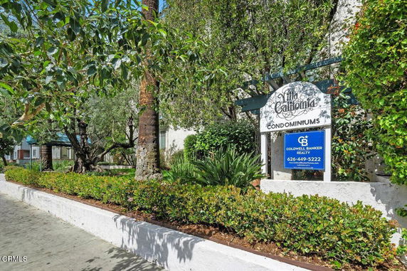 Front view of a condominium complex with a sign and landscaped greenery.