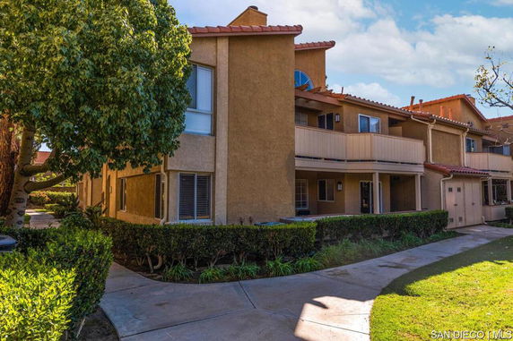 Front view of a two-story residential building with multiple balconies and a sloped roof.