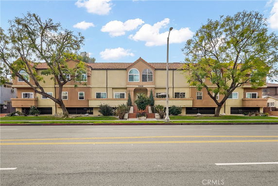 Front view of a multi-story residential building with a central entrance and arched windows.