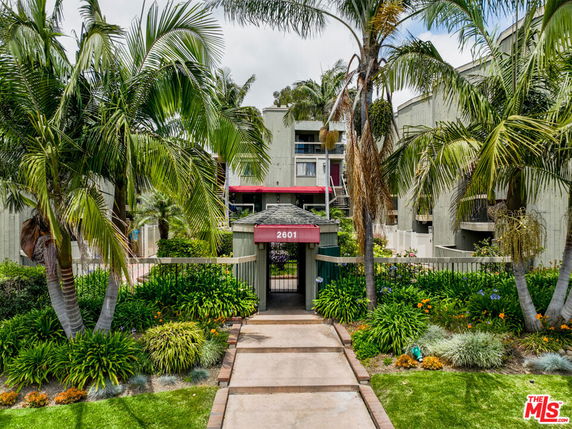 Front view of a multi-story residential building with lush landscaping.