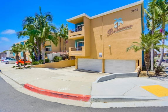 Front view of a two-story building with garages and palm trees.