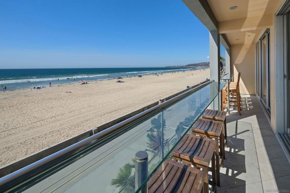 Balcony view overlooking a sandy beach and ocean.