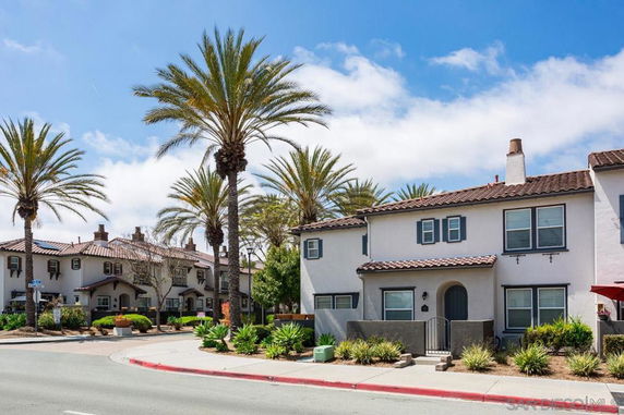 Front view of two-story house with palm trees and arched entrance.