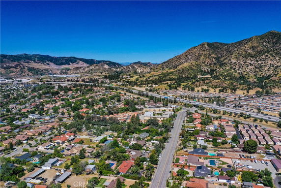 Wide aerial view of a residential area with roads and hills in the background.