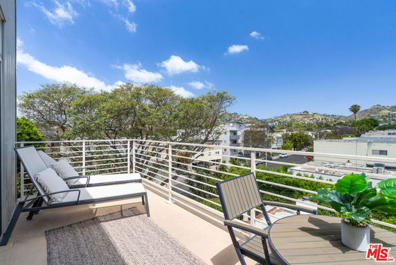Balcony view overlooking surrounding residential area with hills in the background.