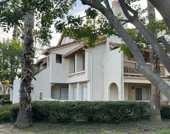 Front view of a two-story house with a balcony and arched doorway.