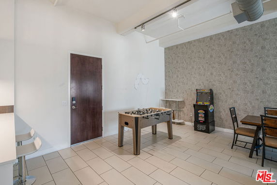 Room with foosball table, arcade machine, and seating area.