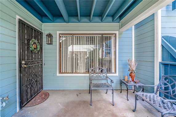 Front view of a house featuring a doorway with a decorative wreath, a large window, and patio furniture.