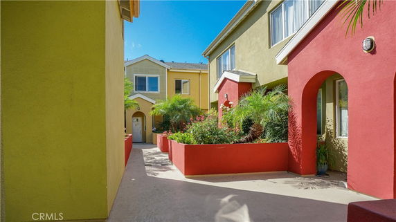 Front view of colorful two-story buildings with archways and gardens.