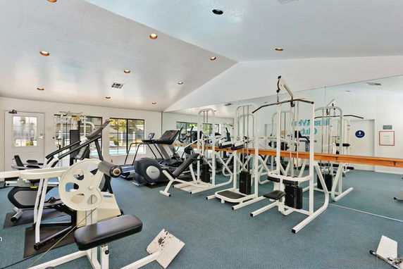 Interior view of a gym with various exercise equipment, including treadmills and weight machines.