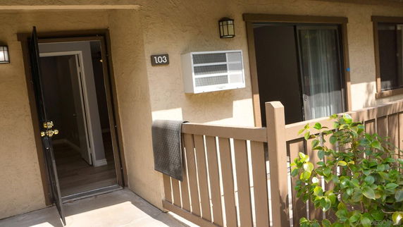 Front view of a residential unit with an open door and window.
