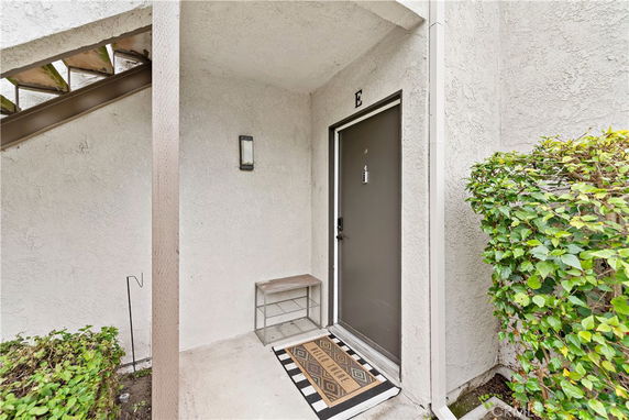 Entrance area with a door marked 'E', small bench, and a welcome mat.