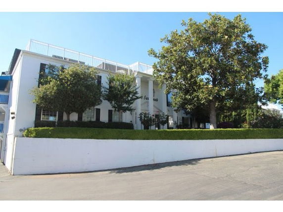 Front view of a large two-story building with greenery in front.