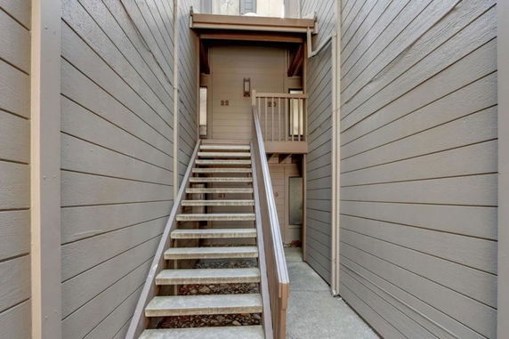Entrance view with stairs leading to the door of a building with wood paneling.