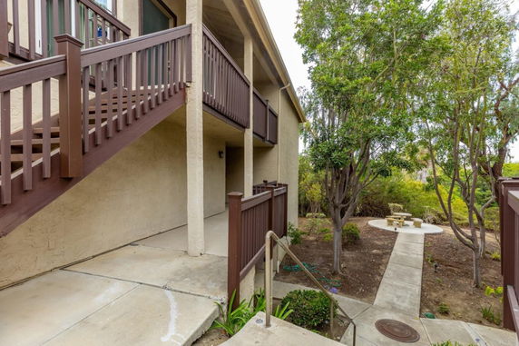 Side view of a multi-story building with an outdoor staircase and adjacent garden area.