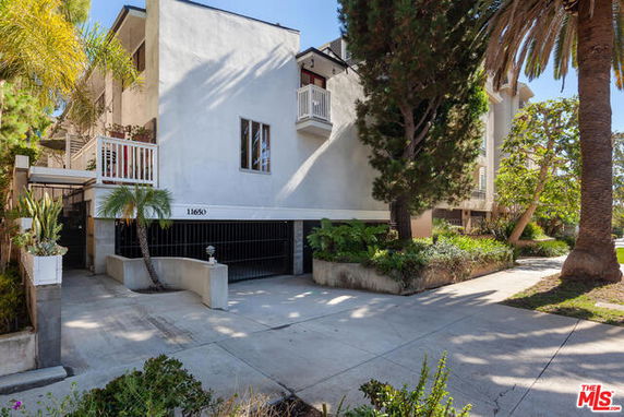 Front view of a multi-story building with balcony and garage.