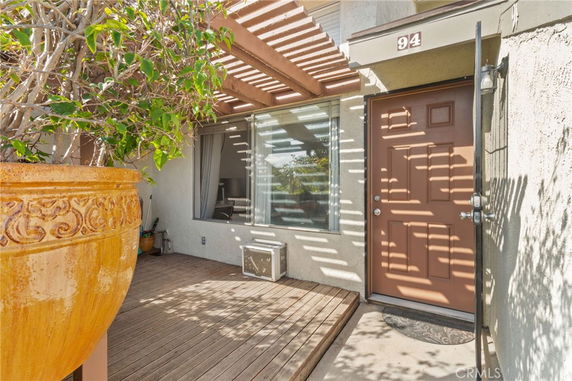 Front view of a house with a wooden deck and a brown door.