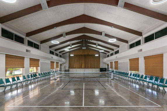 Interior of a large hall with chairs along the walls and a net in the center.