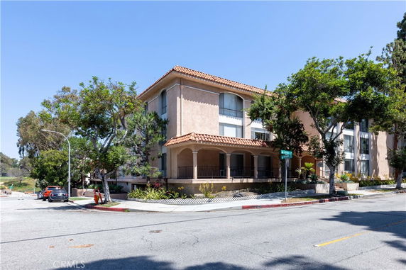 Front view of a multi-story building with a sloped roof and balconies.