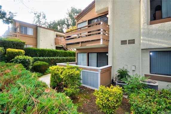 Front view of a multi-story residential building with balconies and surrounding greenery.