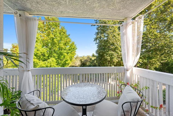 Balcony with a small table and chairs overlooking trees.