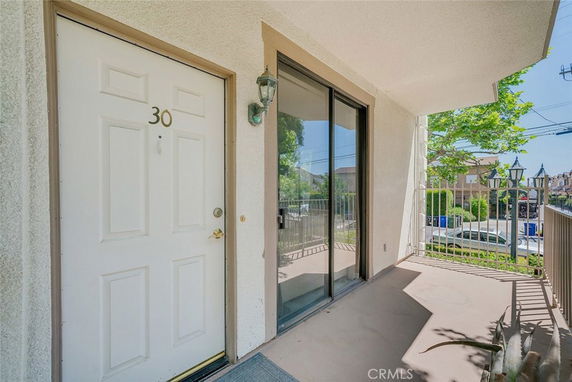 Entrance view of a building with a white door and sliding glass door leading to a small balcony.