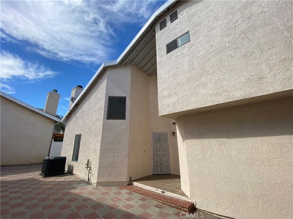 Front view of a two-story house with a beige exterior and a small entrance patio.