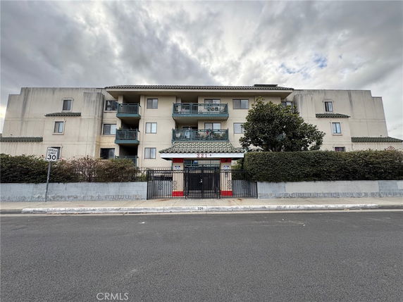 Front view of a multi-story building with balconies and gated entrance.