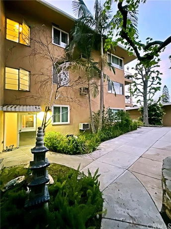 Front view of a multi-story apartment building with a pathway and garden.
