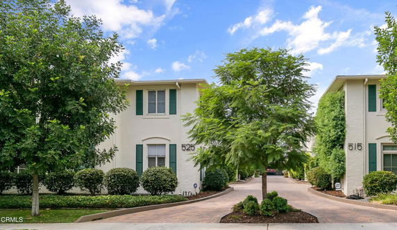 Front view of two-story houses with driveways and green shutters.