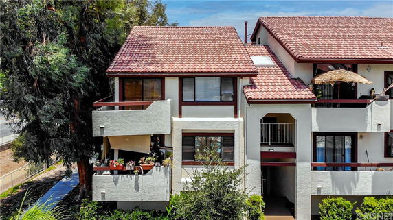 Front view of a multi-story residential building with red tiled roof and balconies.