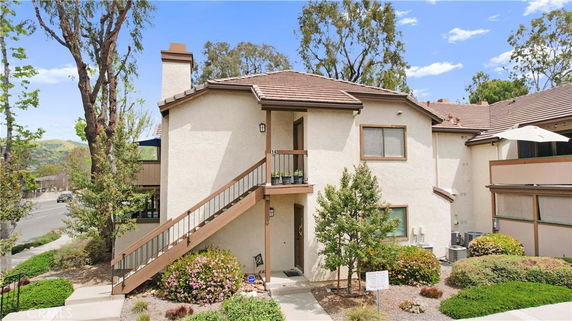 Front view of a two-story house with an exterior staircase and a chimney.