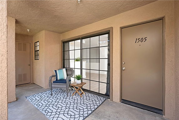 Front view of a house entrance with a door labeled 1505, featuring a small seating area.