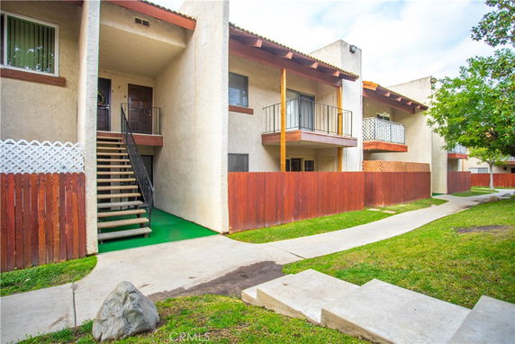 Front view of a multi-story apartment building with balconies and an external staircase.