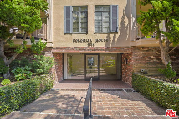 Front view of a Colonial style building entrance with a brick walkway.