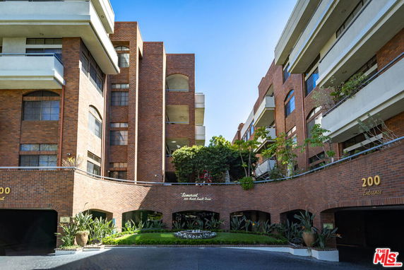 Front view of a multi-story brick apartment building with balconies and an entrance.