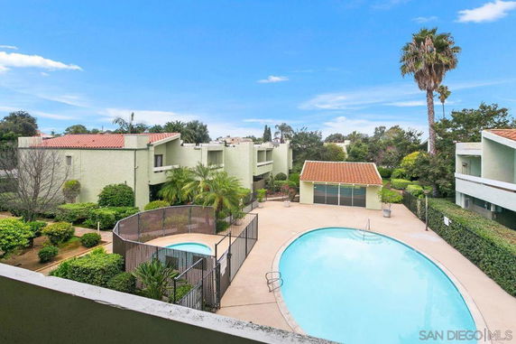 View of an outdoor area with a swimming pool, surrounded by buildings and greenery.
