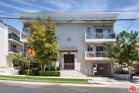 Front view of a multi-story residential building with balconies and a central entrance.