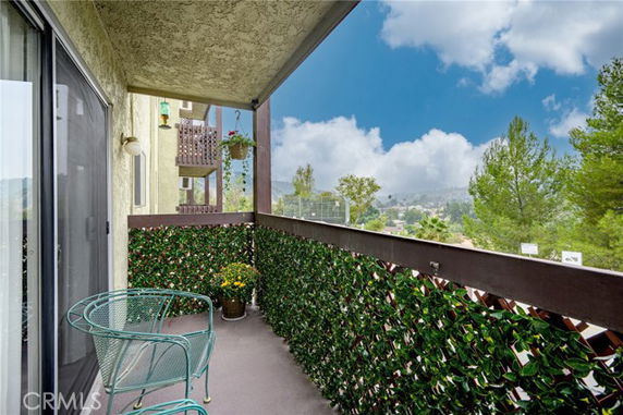 Balcony with chairs offering a panoramic view of the surrounding area and hills in the distance.