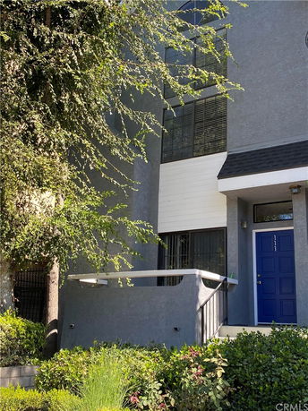 Front view of a multi-story building with a blue door and balcony.